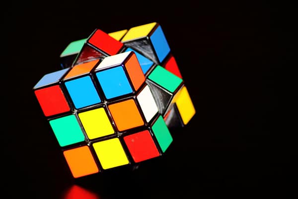 scrambled Rubiks cube mental puzzle with black background balancing on one of its vertices